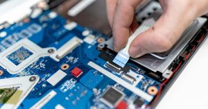 A hand testing and repairing a circuit board that has been extracted for circular recycling, ready to be repurposed in sustainable and refurbished IT hardware.